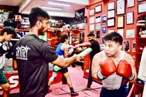Coach Kumar guiding a boxer through dodge practice.