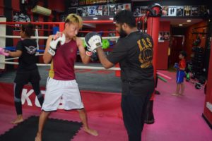 Coach Karthick mentoring a young boxer during training.
