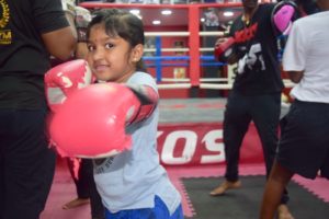 Young girl in pink boxing gloves celebrating with a fist bump.
