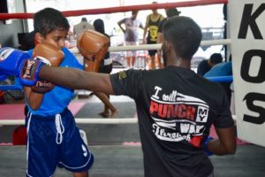 Coach guiding a young boxer through training drills.