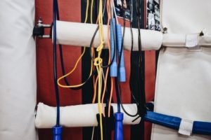 Variety of skipping rope types, thick and thin, messily hung on a bar.