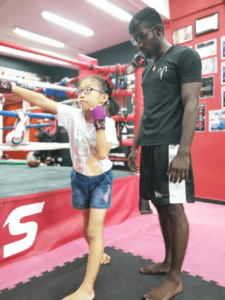Young boxer practicing punches under coach's watchful eye.