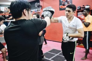 Coach Khai leading a class, demonstrating punches as a student defends